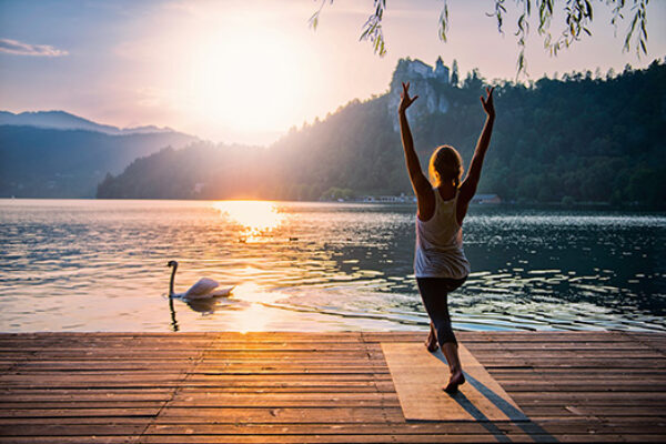 Woman doing Yoga on dock at lake side